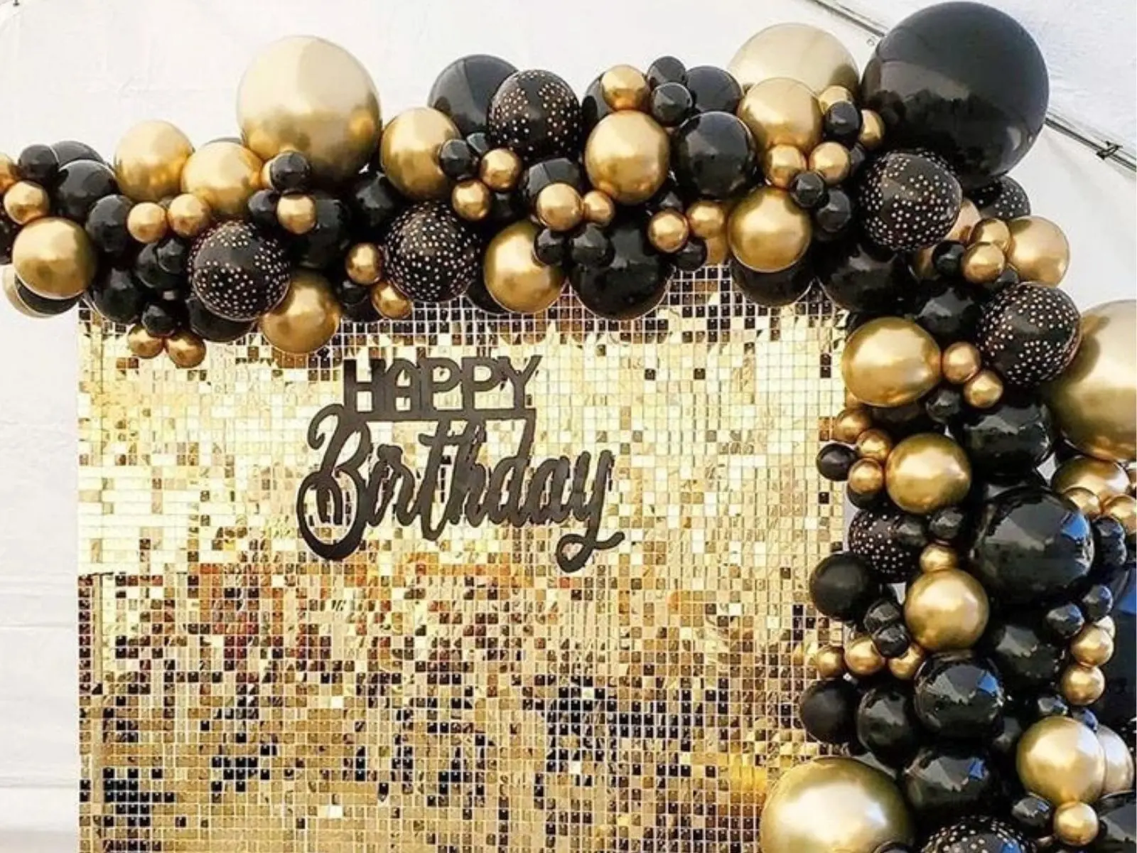 Black and gold organic balloon arch around a birthday backdrop in London
