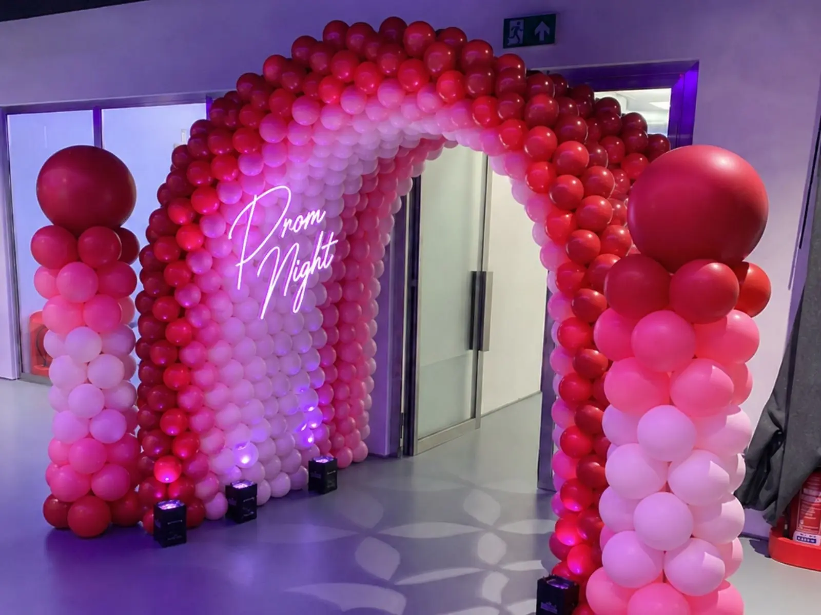 Premium pink balloon arch installation with uplighting at a London prom